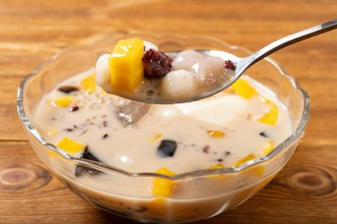 Çimen jölesi, mango, şeftali sakızı, tapyoka, kırmızı fasulye ve jöle karışımı bir kase süt şurubu yemek. yatay bileşiminde