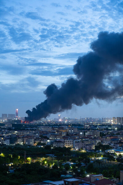a factory catched a fire with lots dark smoke in sunset time vertical composition