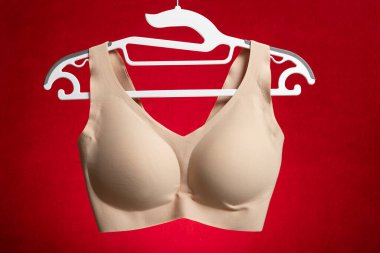 Kırmızı arkaplanda asılı bej sütyen