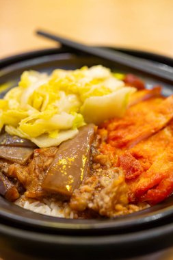 Orlean fırınlanmış tavuk, patlıcan ve sebzeli kil çömlek pilavı dikey kompozisyonda.