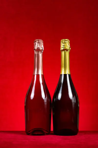 two bottles of sparkling wine on red background at vertical composition