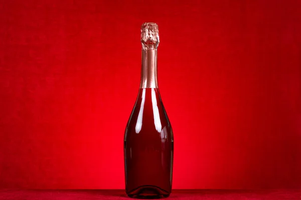 a bottle of sparkling wine on red background at horizontal composition
