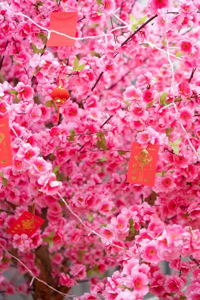 artificial peach blossom and red pockets at vertical composition English translation of the characters are good fortune as one wishes and fortune