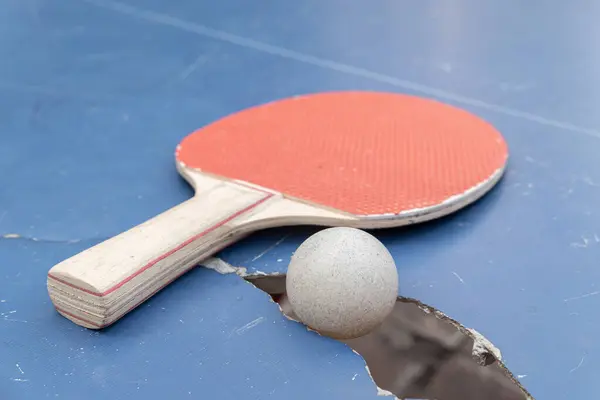 pingpong ball and racket on a damaged table at horizontal composition