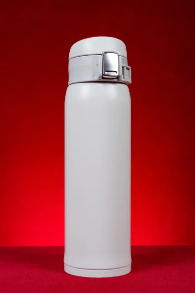 a white vacuum tumbler at vertical composition on red