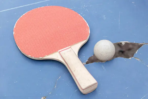 pingpong ball and racket on a damaged table at horizontal composition