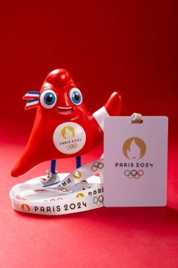 ZHONGSHAN Çin - 23 Mayıs 2024: 2024: 2024 Paris Olimpiyat Oyunları, dikey kompozisyonda kırmızı arka planda IC kartı ile Phryge maskotu.