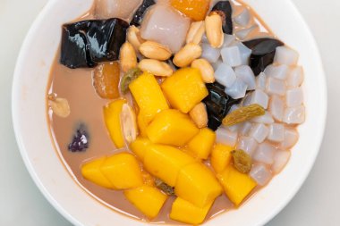 Çim jölesi, mango, şeftali sakızı, tapyoka, kırmızı fasulye vb. ile karıştırılmış milktea aromalı şurup kasesi. yatay bileşiminde