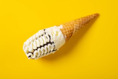 Üst manzara vanilya ve çikolata aromalı dondurma külahı sarı arka planda