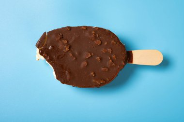 Mavi arka planda ısırık izi olan çikolatalı buzlu dondurma.