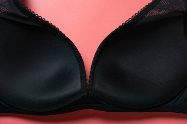 Pembe arka plandaki kadınlar için siyah bir sütyenin içinde.