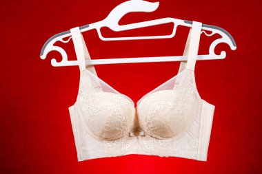 Kırmızı arkaplanda asılı bej sütyen