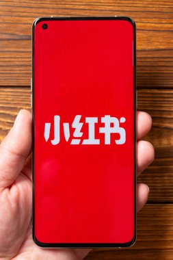 ZHONGSHAN Çin-28 Ocak 2025: Dikey kompozisyonda Rednote logosu olan bir cep telefonu tutan adam.