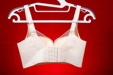 Kırmızı arkaplanda asılı bej sütyen