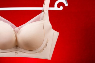 Kırmızı arkaplanda asılı bej sütyen