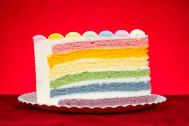 yatay kompozisyonda kırmızı arkaplan üzerinde gökkuşağı renkleri pasta