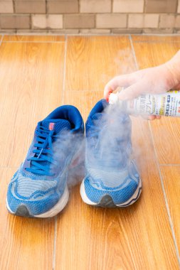 ZHONGSHAN Çin-13 Nisan 2025: Bir ayakkabıya dikey kompozisyonda deodorant ve deodorant sıkmak.