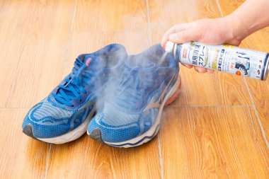 ZHONGSHAN Çin-13 Nisan 2025: yatay kompozisyonda bir ayakkabıya dezenfektan ve deodorant sıkmak.
