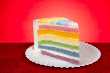 yatay kompozisyonda kırmızı arkaplan üzerinde gökkuşağı renkleri pasta