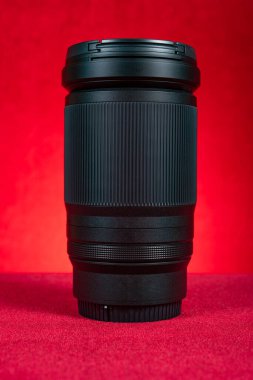 Dikey bileşimde kırmızı zemin üzerinde bir kamera lensi