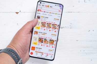 Zhongshan, Çin-25 Nisan 2025: cep telefonu kullanan ve yatay kompozisyonda JD 'de yiyecek arayan adam.