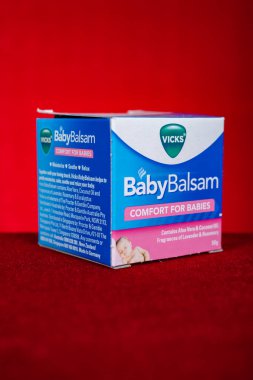 ZhongShan Çin - Ocak 1,2023: Kırmızı arka plan dikey kompozisyonu üzerine bebek balsamı.