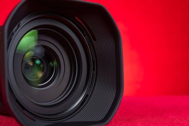 yatay bileşimde kırmızı zemin üzerinde bir kamera lensi