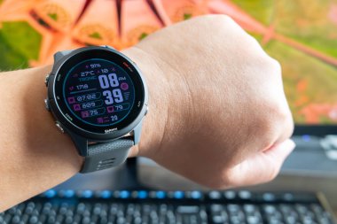 ZhongShan Çin-20 Mayıs 2025: Masaüstü önünde Garmin Forerunner 255 spor saati olan bir adam kolu.