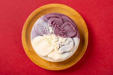 Üst manzara çiçek şekli beyaz ve mor ay pastası kırmızıda.