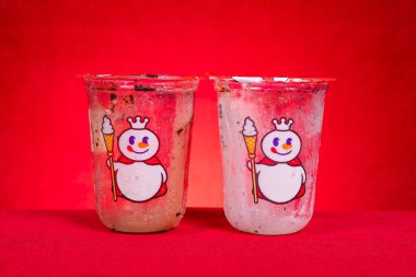 ZHONGSHAN China-June 14 2025: empty cups of Mixue Crispy Grand Sundae and Snow King Sundae on red background.