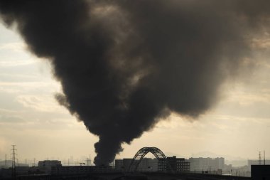 Sabahın erken saatlerinde yanan uzak bir kasaba. Yoğun, siyah bir duman çıkarıyorlar.