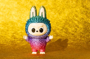 ZHONGSHAN Çin - 17 Temmuz 2025: Çok renkli Labubu Pop Mart bebeği altın arka planda gölgesi olan.