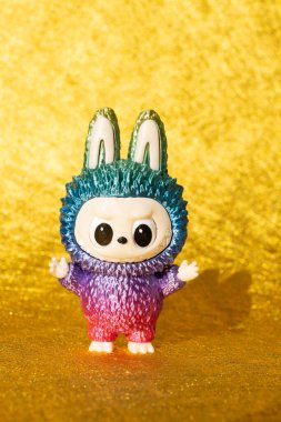 ZHONGSHAN Çin-17 Temmuz 2025: Çok renkli Labubu Pop Mart bebeği dikey kompozisyonda altın bir arka plan üzerinde gölge.