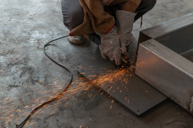 Yetenekli bir işçi öğütücüyle demir boru kesiyor.