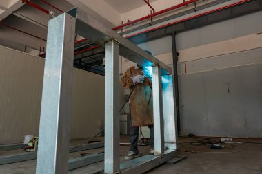 Yatay bileşimi olan bir fabrikada kaynak yapan işçiler.