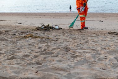 Temizlik işçisi sahildeki çöpleri topluyor.