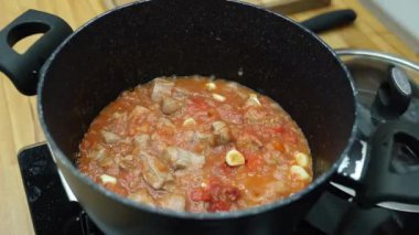 4k Şef sıcak tavada domates soslu biftek pişiriyor.