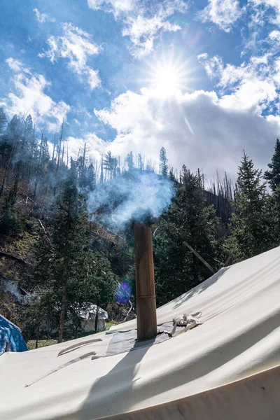 テント内のキャンプストーブからの換気のためのテントの上の煙突から煙が立ち上がり 冬のキャンプ中暖かい滞在 — ストック写真