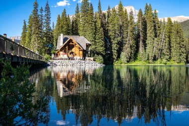 British Columbia, Kanada - 11 Temmuz 2022: Yoho Ulusal Parkı 'nda sakin bir suyla bir yaz akşamı Emerald Lake Lodge restoranı ve köprüsü manzarası