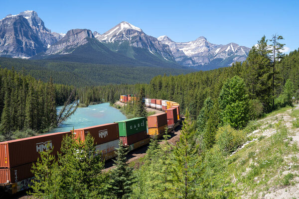 Banff, Alberta, Canada - July 11, 2022: Colorful freight train passes through Morants Curve in Banff National Park on a sunny summer day
