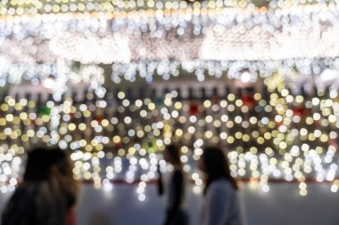 Christmas lights outside at night, intentionally defocused, with blurry people walking by. Useful for backgrounds
