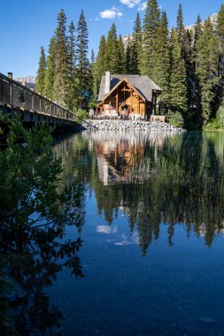 British Columbia, Kanada - 11 Temmuz 2022: Yoho Ulusal Parkı 'nda sakin bir suyla bir yaz akşamı Emerald Lake Lodge restoranı ve köprüsü manzarası