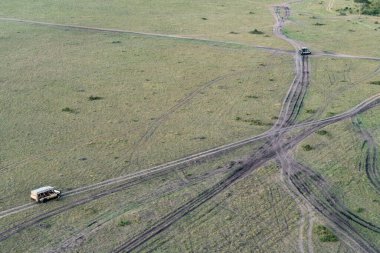Kenya Afrika 'daki Masai Mara Bölgesi' nden geçen iki safari aracının hava görüntüsü.