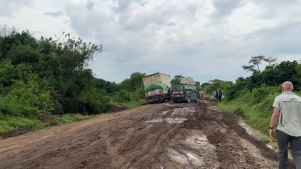 非洲乌干达 2023年3月24日 一辆大型半卡车卡在泥泞 车辙斑斑 未铺面的道路上 游客们正走过去绕开滞留的车辆时发生了车祸 — 图库视频影像