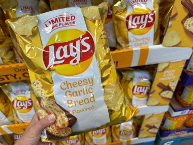Maple Grove, Minnesota - 8 Nisan 2023: Hand, Sams Club 'da satılık bir paket peynirli sarımsaklı patates cipsi tutuyor.