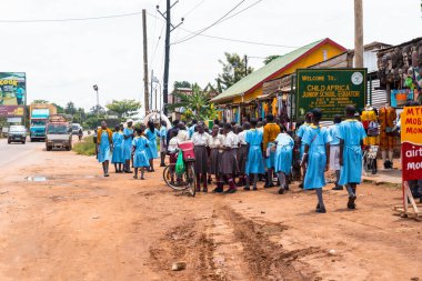 Kayabwe, Uganda - 21 Mart 2023: Okul üniformalı çocuklar Ekvator hattının turistik alanındaki bir pazarın yakınında yürüyorlar