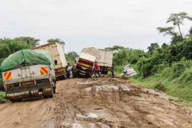 Uganda, Afrika - 24 Mart 2023: Çamurlu, rutubetli, asfaltsız yolda sıkışmış büyük bir tırın kaza mahalli