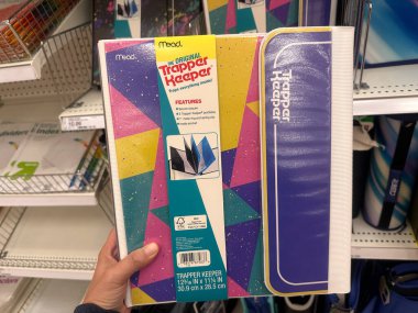 Plymouth, Minnesota - July 30, 2023: Hand holds up a throwback 1990s trapper keeper portfolio folder system on sale at a Target store clipart