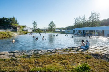 Fludir, İzlanda - 8 Temmuz 2023: İnsanlar İzlanda 'nın en eski jeotermal havuzu olan ünlü Gizli Lagoo' da banyo yapıyorlar.
