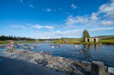 Fludir, İzlanda - 8 Temmuz 2023: İnsanlar İzlanda 'nın en eski jeotermal havuzu olan ünlü Gizli Lagoo' da banyo yapıyorlar.